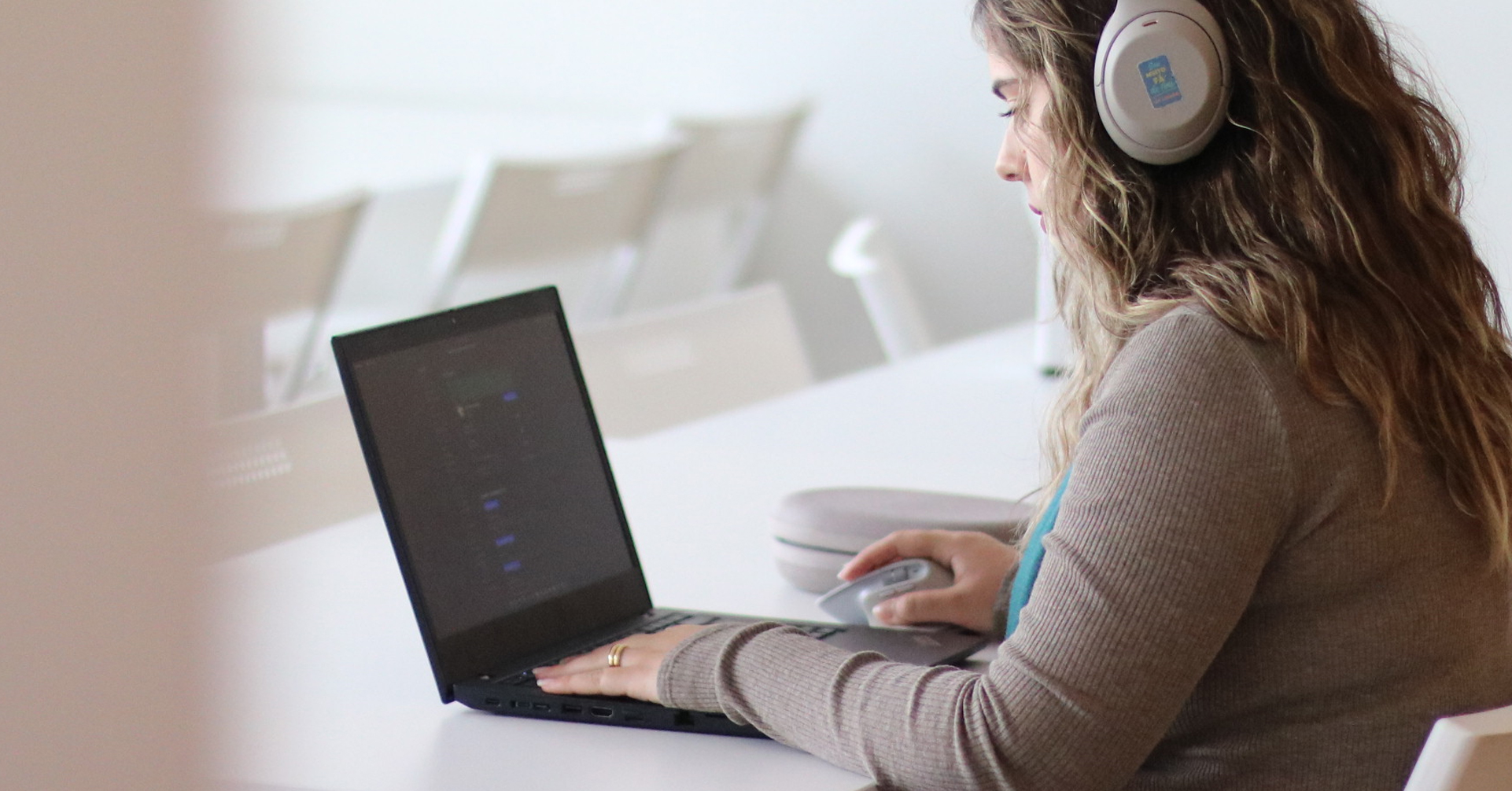 A Fabamaq team member focusing on her work with a laptop, wearing headphones, during an online language class.